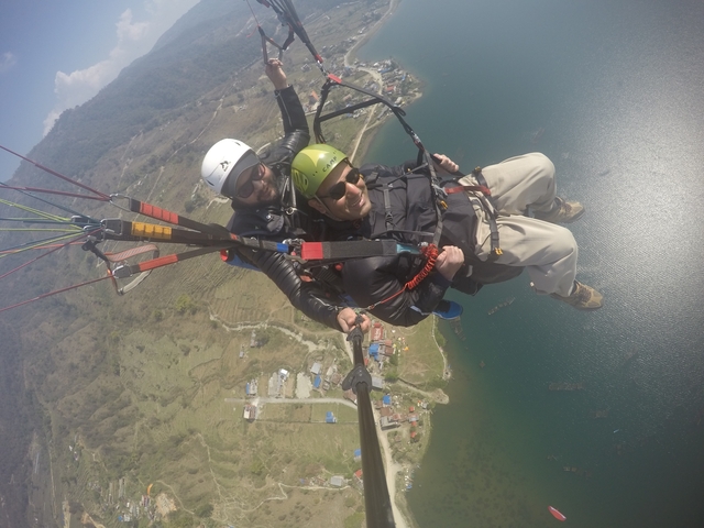       Two people paragliding with a view of a lake and mountains.
  