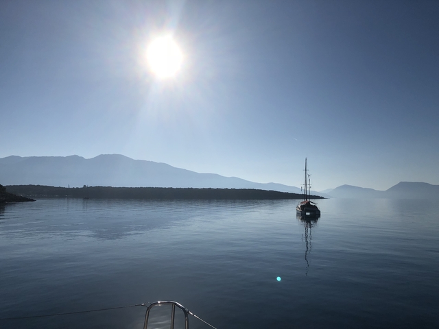       A boat on calm waters with the sun shining above.
  