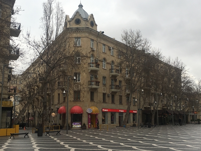       Corner building with balconies on a city street.
  