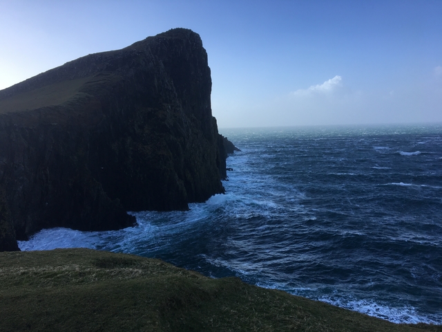 A rocky seaside cliff with crashing waves.