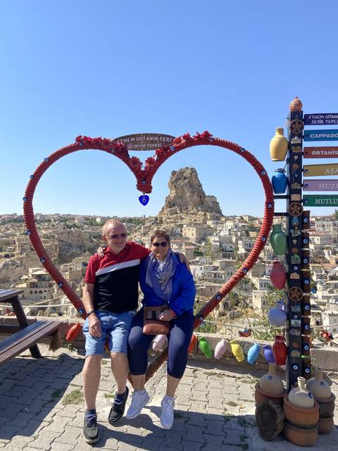       Couple posing with a heart-shaped decoration in the background.
  