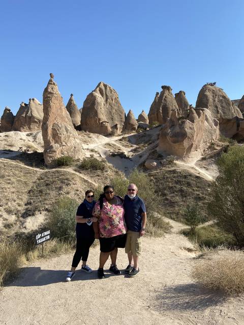       Three people posing in a rocky landscape with distinctive formations.
  