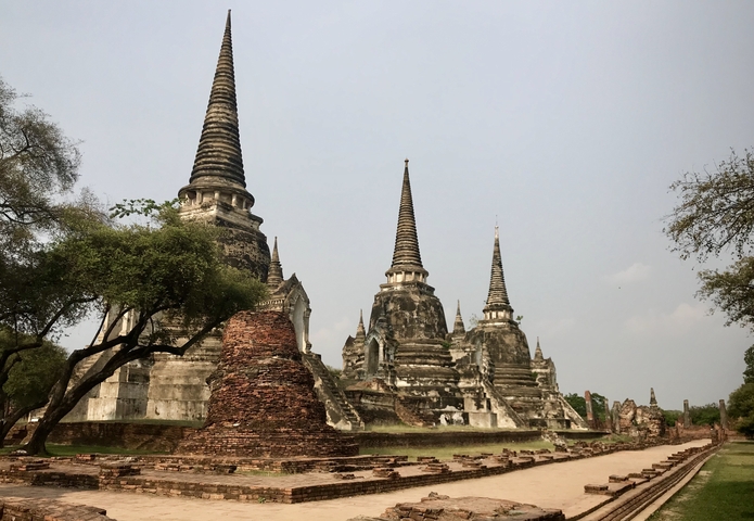 Ancient temple ruins with spires and trees surrounding it.