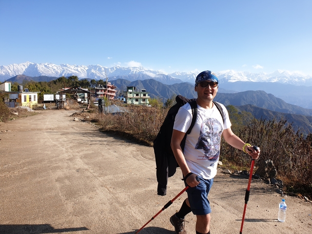       Smiling man posing on a path in front of mountains.
  