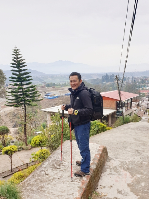       Man with hiking gear on a hillside.
  