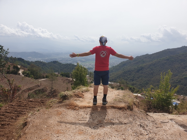       Man standing with open arms on a mountain trail.
  