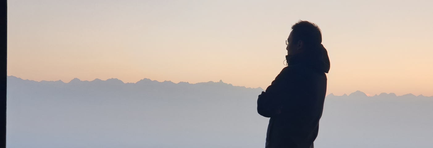       Silhouette of a person gazing at mountains during sunrise.
  
