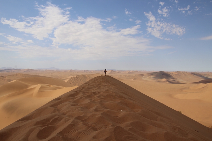 Single person standing on a vast sand dune.