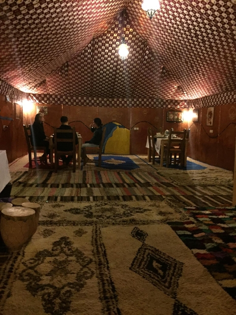 People dining in a carpeted tent with ambient lighting.