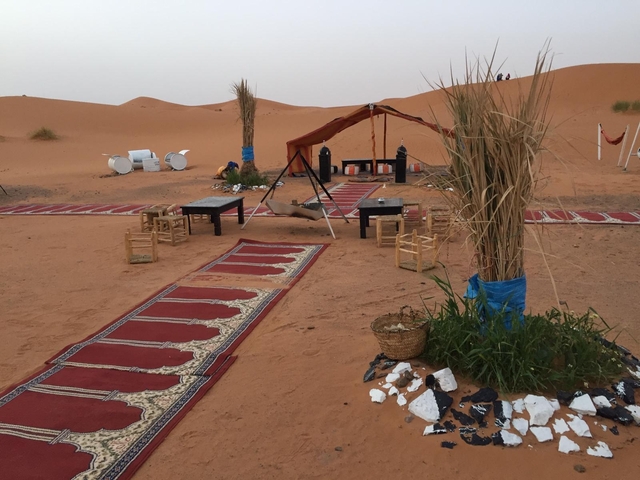 Outdoor desert area with tents and a seating arrangement.