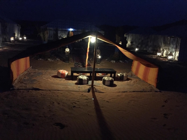 Tent set up in a desert camp illuminated at night.