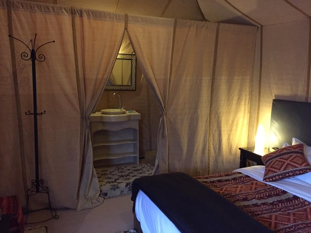 Interior view of a tent with beds and a wash basin.