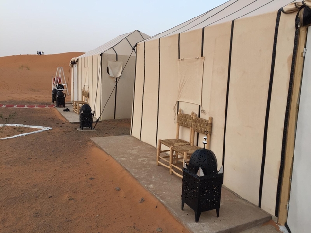 Desert camp with tents and lanterns placed at the entrance.