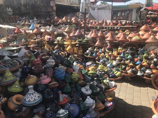 Colorful array of tagines and ceramics displayed outdoors.