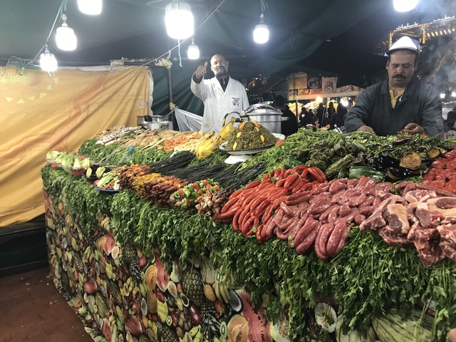 A vibrant marketplace with various meats and vegetables displayed.