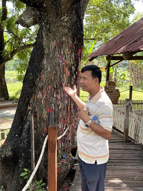       Man presenting bracelets tied to a tree
  