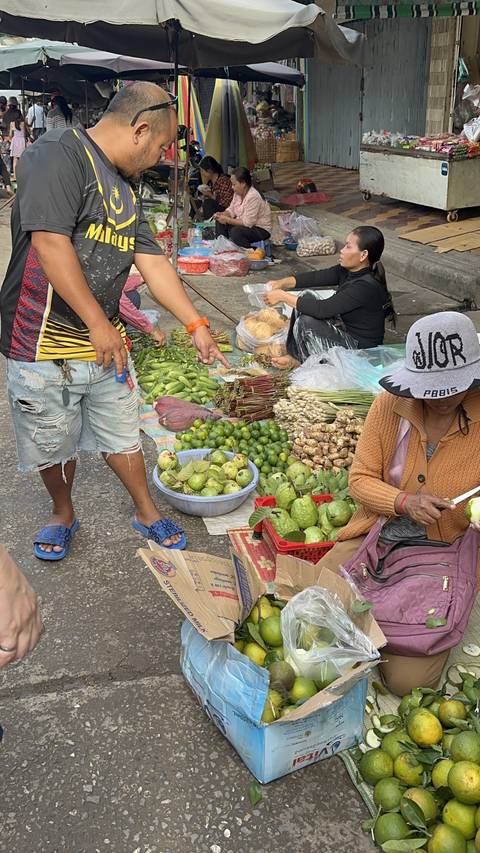       People selling fruits and vegetables at a market.
  