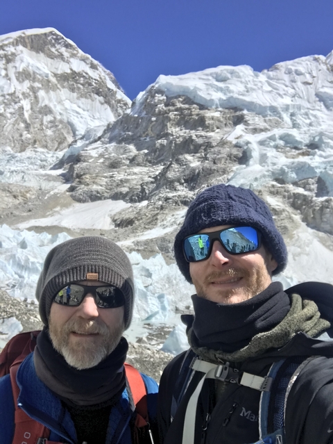 People posing in front of a snowy mountain landscape.