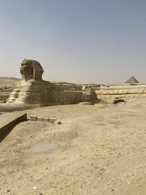 View of the Sphinx with the pyramids in the background.
