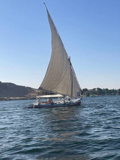 Sailboat on water with a scenic hillside background.