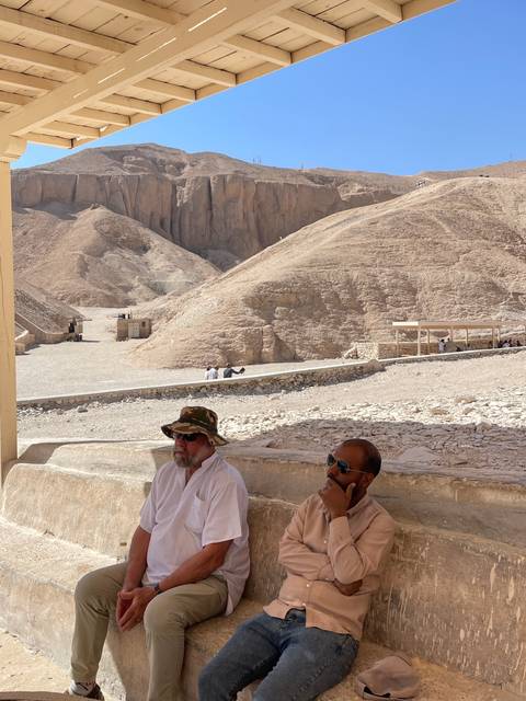 People sitting against a large rock formation.