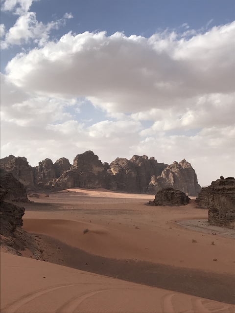 Rock formations under a partly cloudy sky in a desert landscape.
