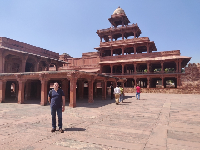       Tourists exploring an ancient multi-tiered red sandstone structure.
  