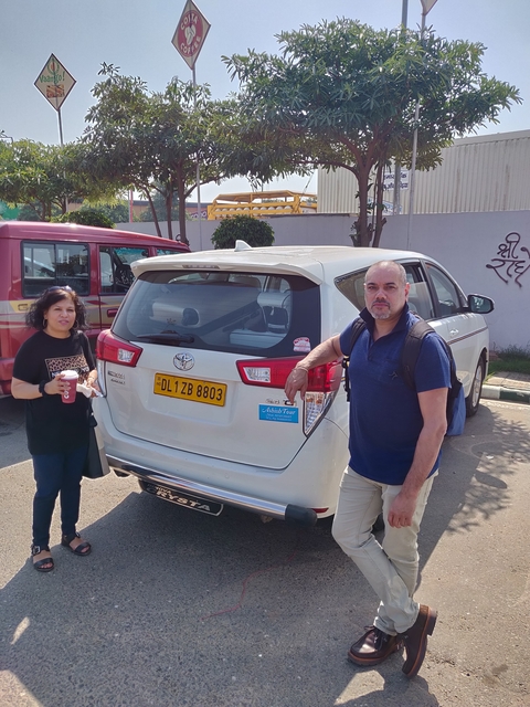       Two people standing near a parked car with a visible license plate.
  