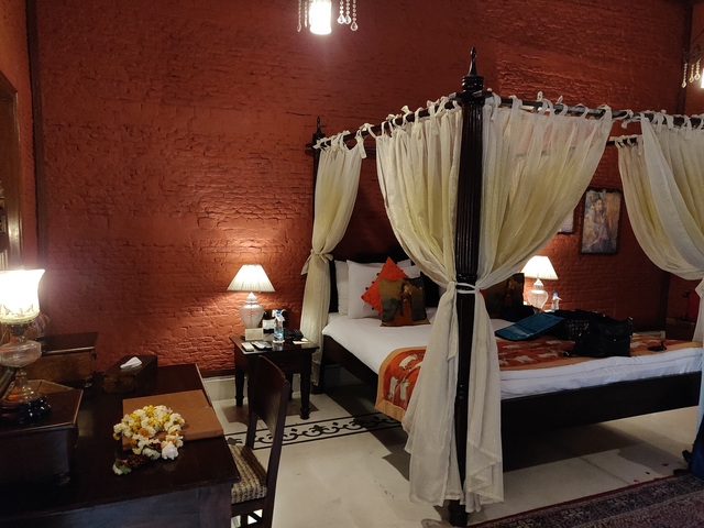       A luxurious room with a four-poster bed and warm lighting.
  