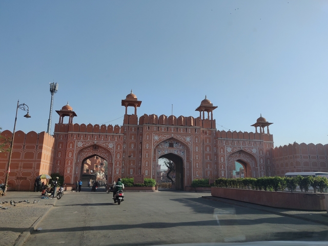       A large gate with intricate designs in a city setting.
  