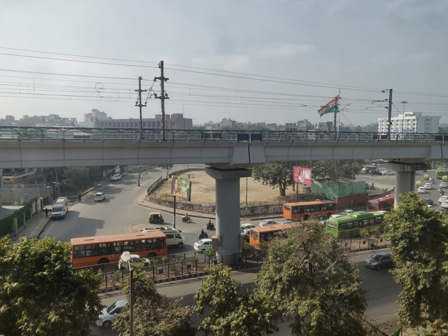 View of a busy city road with elevated railway tracks.