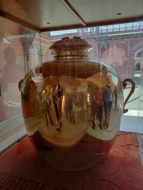 Large polished urn with reflections of people.