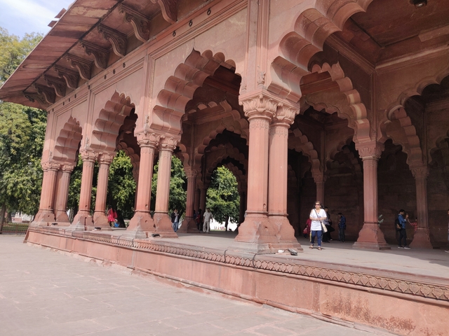       Visitors exploring a red sandstone architecture with arches.
  