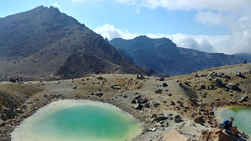 Hikers and volcanic landscape with mineral lakes.
