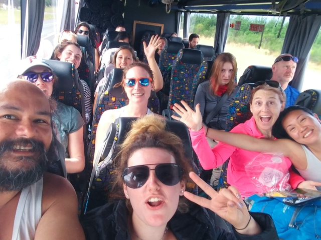 Group of people posing and enjoying a bus ride.