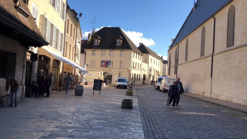       A street view with people walking on a cobblestone road.
  
