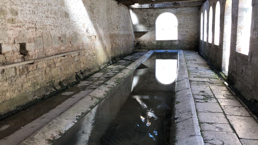       An old stone water basin inside an historic building.
  