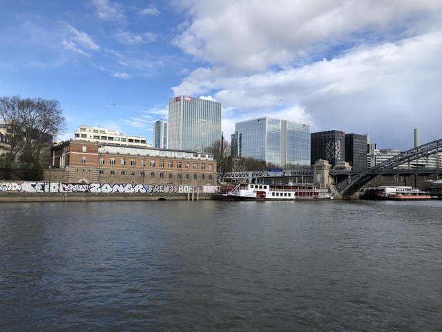       A riverside cityscape with modern buildings and a bridge.
  
