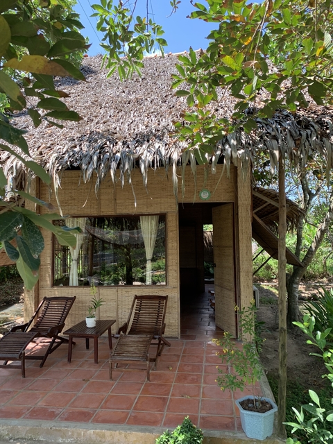       A rustic hut with a thatched roof and wooden chairs.
  
