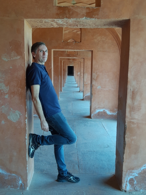       A person leaning against a column in a historical site.
  