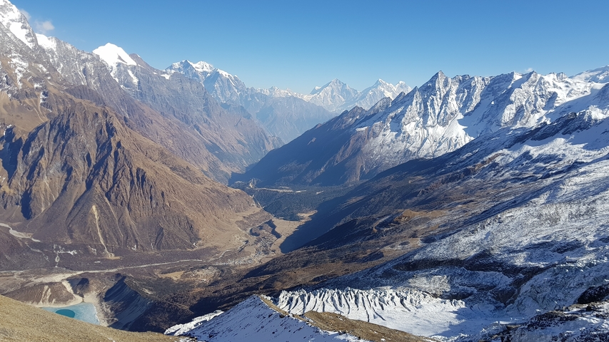       Panoramic view of snow-capped mountains and a valley.
  