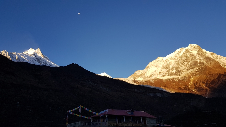       Mountains with a house in the foreground and prayer flags.
  