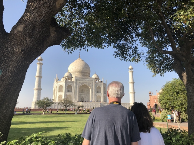 Two people at the Taj Mahal with trees framing the view.