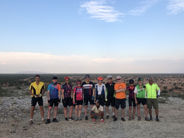 Group of cyclists posing on a rocky terrain with a landscape in the background.