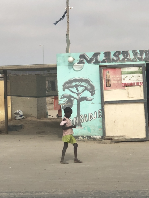 A child standing in front of a painted wall with signs and drawings.