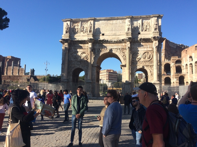 Tourists near the Arch of Constantine with the Colosseum.