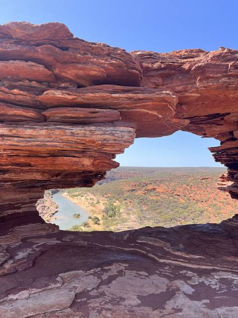 Rock formations with a view of greenery through a gap.
