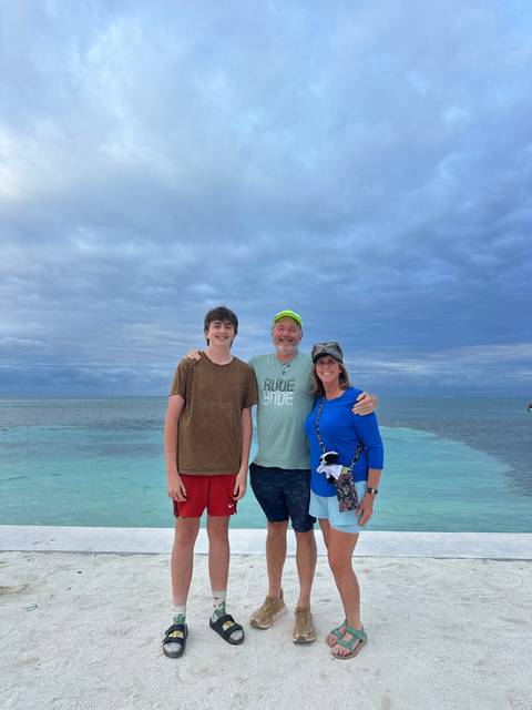 Three people posing on a beach.