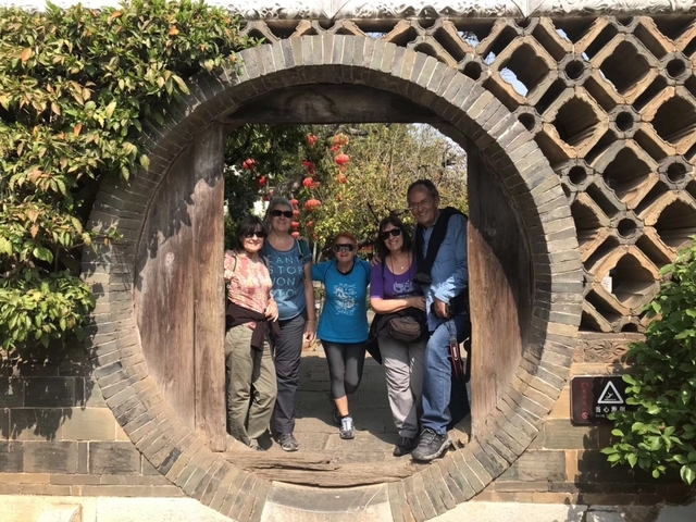       Tourists posing in front of a traditional Chinese gate.
  