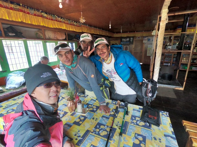       Four men posing together in a room with mountain expedition gear.
  